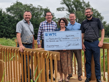 Wamego Telecommunications Company representatives met with members of Meadowlark’s leadership team to present a donation to support this year’s Paving the Way campaign. Standing on one of the Loop Trail bridges is (from left) Lonnie Baker, Meadowlark CEO;